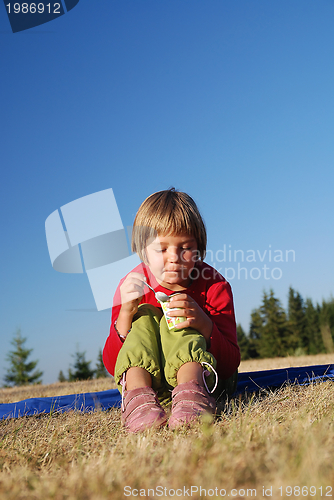 Image of cute little girl eating healthy food outdoor