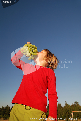 Image of happy girl with grape outside