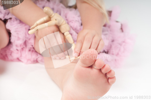 Image of Foot and fingers of little girl and wooden toy