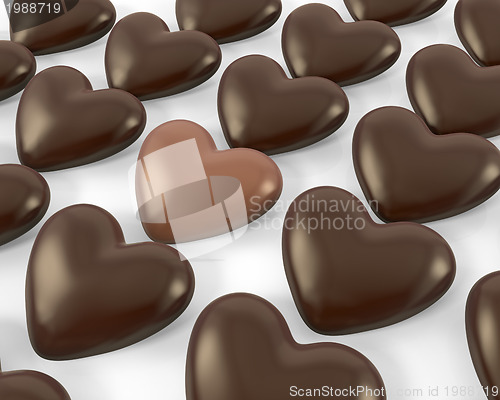 Image of Heart shaped milk chocolate candy between dark ones