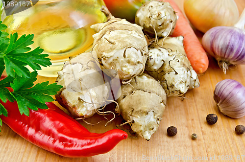 Image of Jerusalem artichokes with vegetables and oil on board