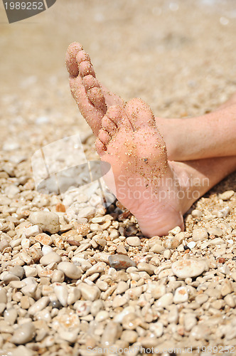 Image of Relaxation on beach, detail of male feet