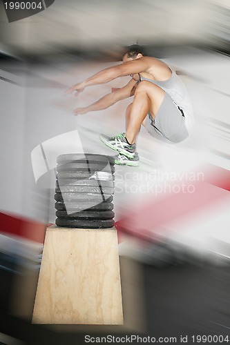 Image of Athletic man jumping over a lot of weights 