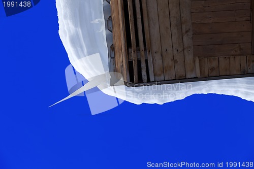 Image of Snowdrift and big icicle on wooden roof