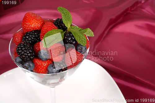 Image of Fresh berries topped with mint in a martini glass resting on a w