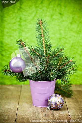 Image of bucket with christmas fir tree and purple decorations 