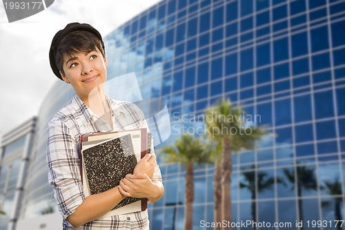 Image of Mixed Race Female Student Holding Books in Front of Building