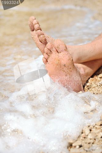 Image of Relaxation on beach, detail of male feet