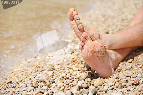 Image of Relaxation on beach, detail of male feet