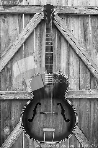 Image of Monochrome Vintage Acoustic Guitar On Fence