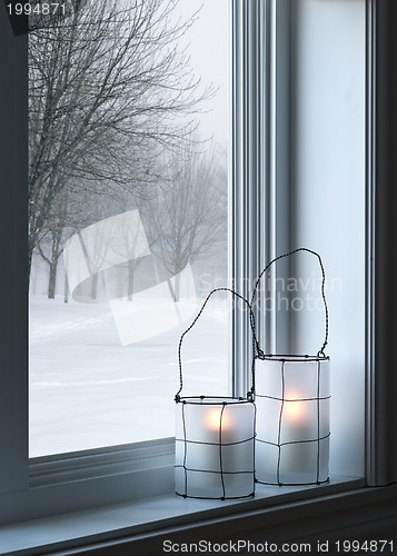 Image of Cozy lanterns and winter landscape seen through the window