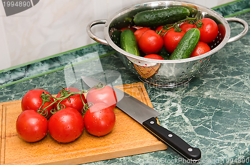 Image of red tomato and knife on board