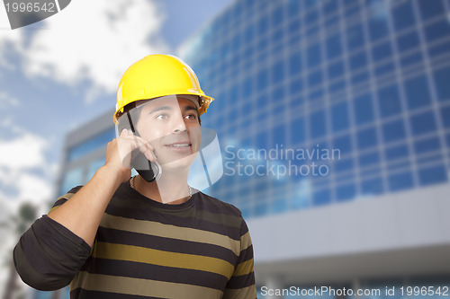 Image of Hispanic Male Contractor on Phone in Front of Building