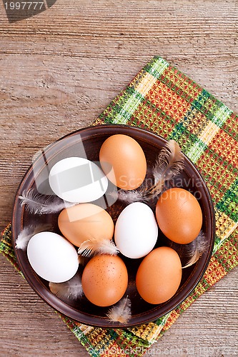Image of eggs in a plate, towel and feathers 
