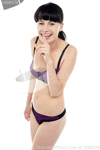 Image of Gorgeous bikini model gesturing silence with a smile