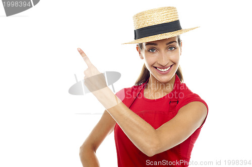 Image of Smiling woman wearing straw bowler hat pointing away