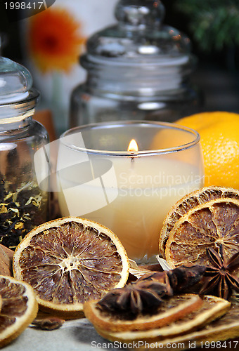 Image of Candle, cinnamon sticks and dry orange