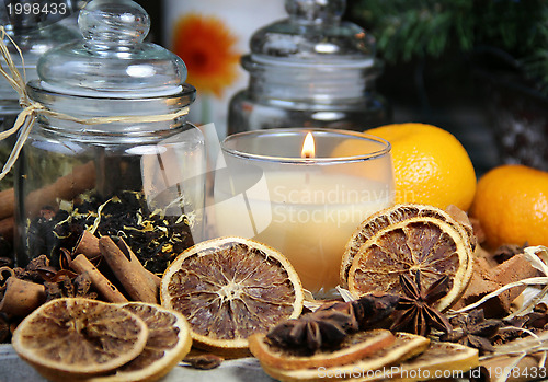 Image of Candle, cinnamon sticks and dry orange