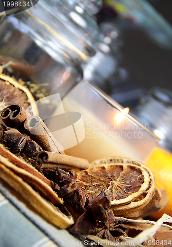 Image of Candle, cinnamon sticks and dry orange