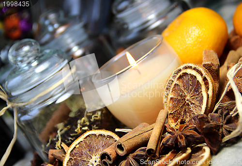 Image of Candle, cinnamon sticks and dry orange