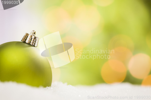 Image of Green Christmas Ornaments on Snow Over an Abstract Background