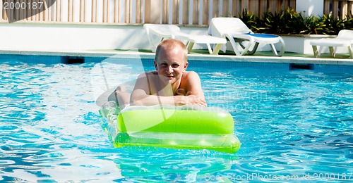 Image of young man is swimming with air mattress in pool