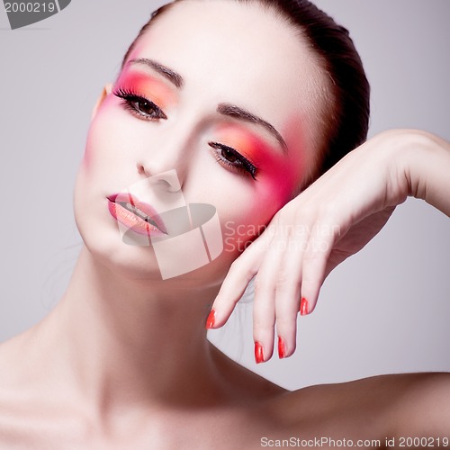 Image of woman portrait with extreme make up in orange and pink
