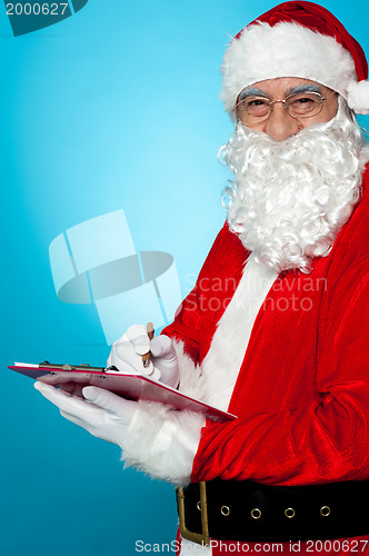 Image of Santa Claus making notes in the wish list