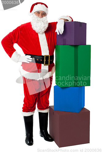 Image of Santa Claus posing beside pile of gifts on Christmas eve