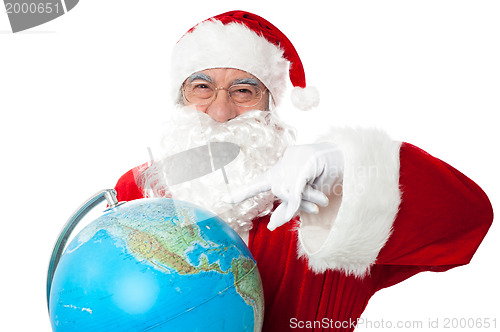 Image of Expressionistic Santa pointing at north pole on globe