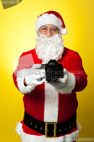 Image of Santa Claus holding up his brand new DSLR