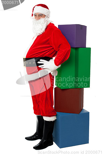 Image of Santa leaning over colorful pile of Xmas presents