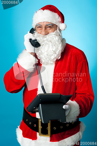 Image of Modern Santa passing greetings over a phone call