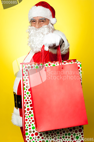 Image of Cheerful Santa holding vibrant colored shopping bags