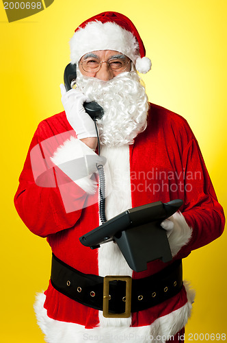 Image of Smiling aged Santa attending phone call