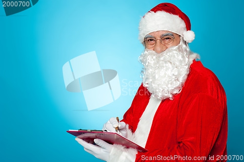 Image of A thoroughly modern Santa claus checks his list on clipboard