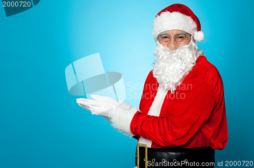 Image of Santa against blue background posing with open palms