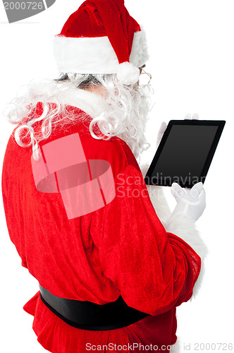 Image of Back view of Santa looking at tablet device screen