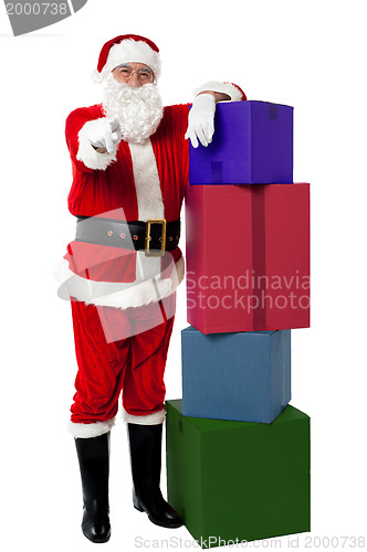 Image of Smiling senior Santa posing beside colorful stack of Xmas presents