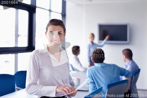 Image of business woman with her staff in background at office