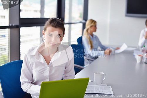 Image of business woman with her staff in background at office