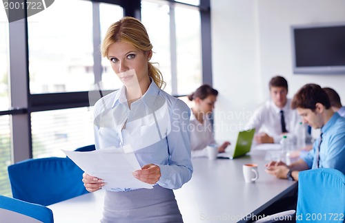 Image of business woman with her staff in background at office