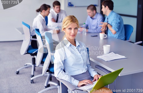 Image of business woman with her staff in background at office