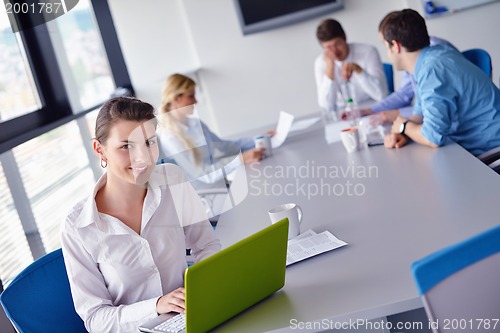 Image of business woman with her staff in background at office