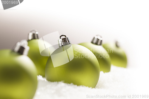 Image of Green Christmas Ornaments on Snow Over a Grey Background