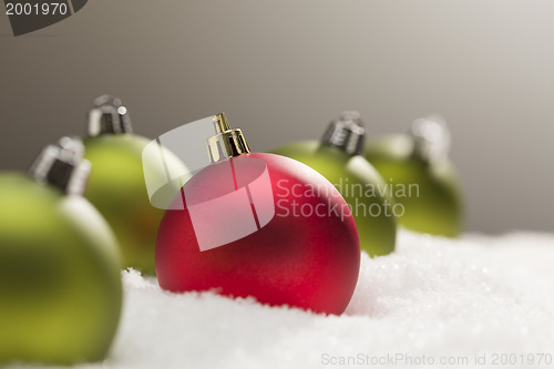 Image of Red and Green Christmas Ornaments on Snow Over Grey