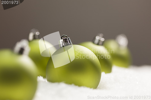 Image of Green Christmas Ornaments on Snow Over a Grey Background