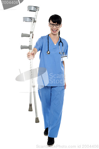 Image of Orthopedic doctor walking towards camera with crutches in hand