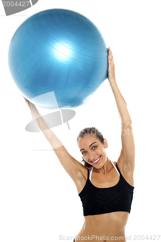 Image of woman holding big blue pilates ball above her head