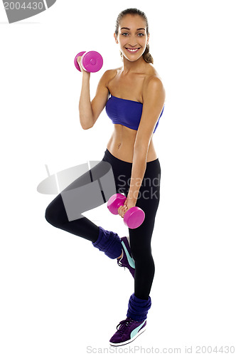 Image of Slim young woman working out with dumbbells